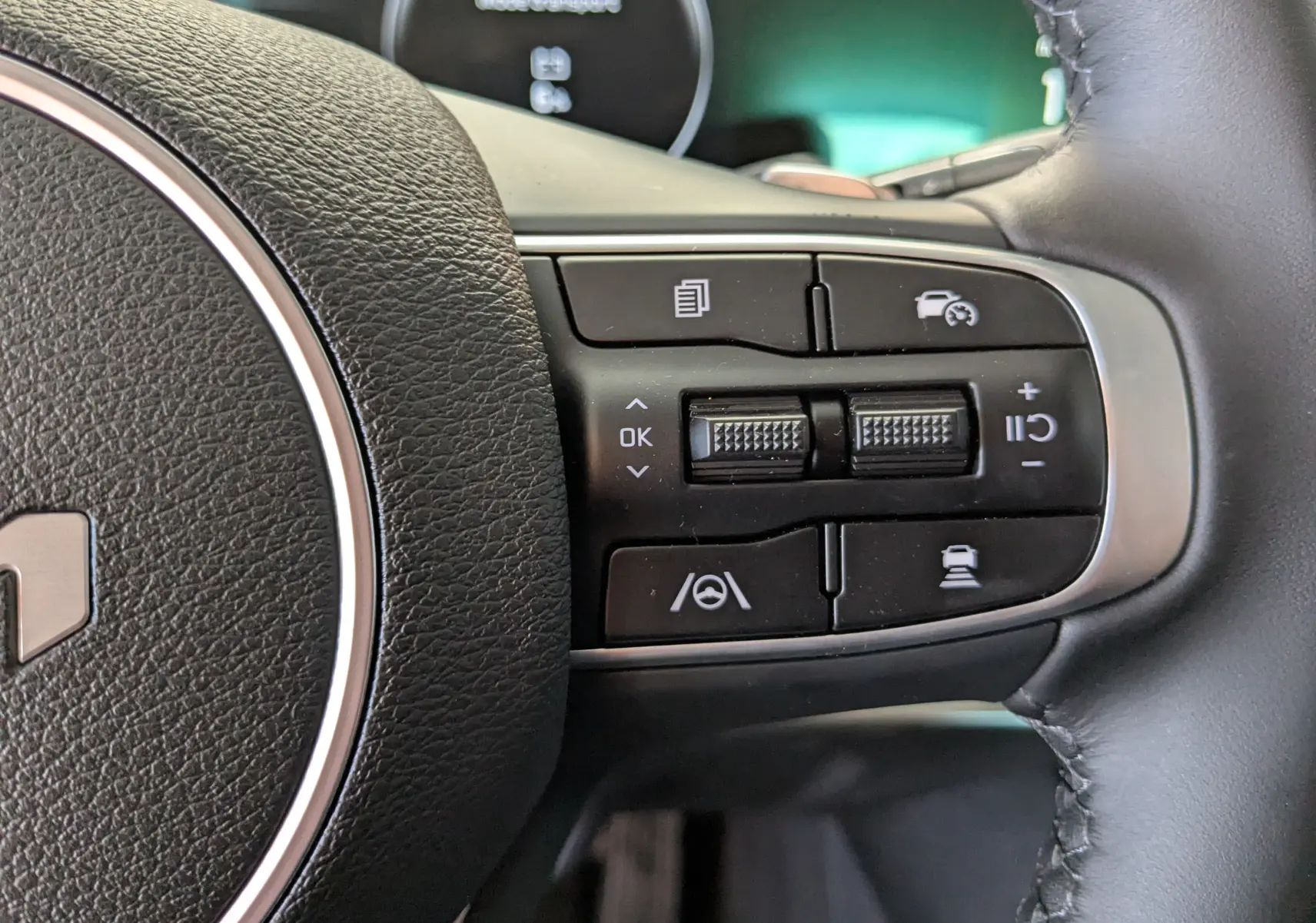 Gros plan sur les commandes à droite du volant en cuir du Kia Sportage gris Eclipse MY25, avec boutons de régulateur et assistances.