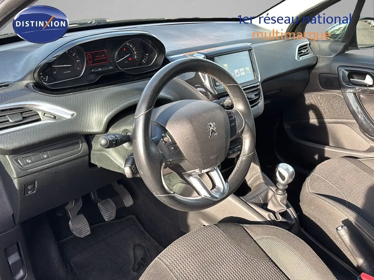 Intérieur de la Peugeot 208 1.2 PureTech 110 Tech Edition 2019, tableau de bord et volant noir côté conducteur.