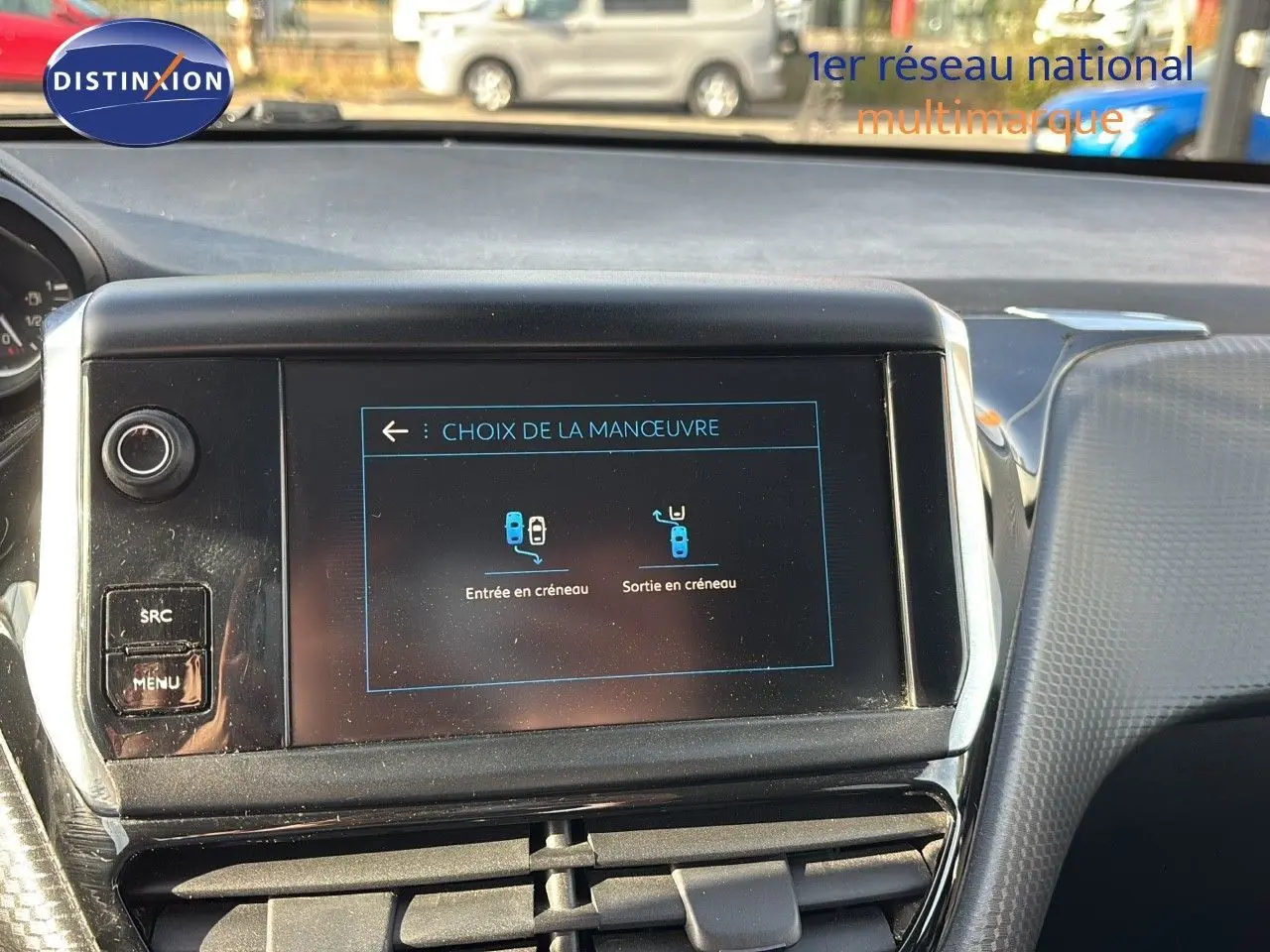 Écran central tactile du tableau de bord d'une Peugeot 208 noire perle métal, affichant le choix de manœuvre de stationnement.