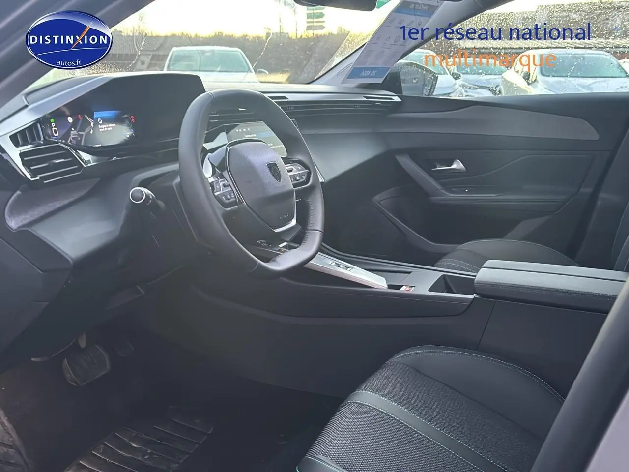 Vue intérieure côté conducteur de la Peugeot 308 gris artense 2025, avec tableau de bord numérique et volant multifonction.