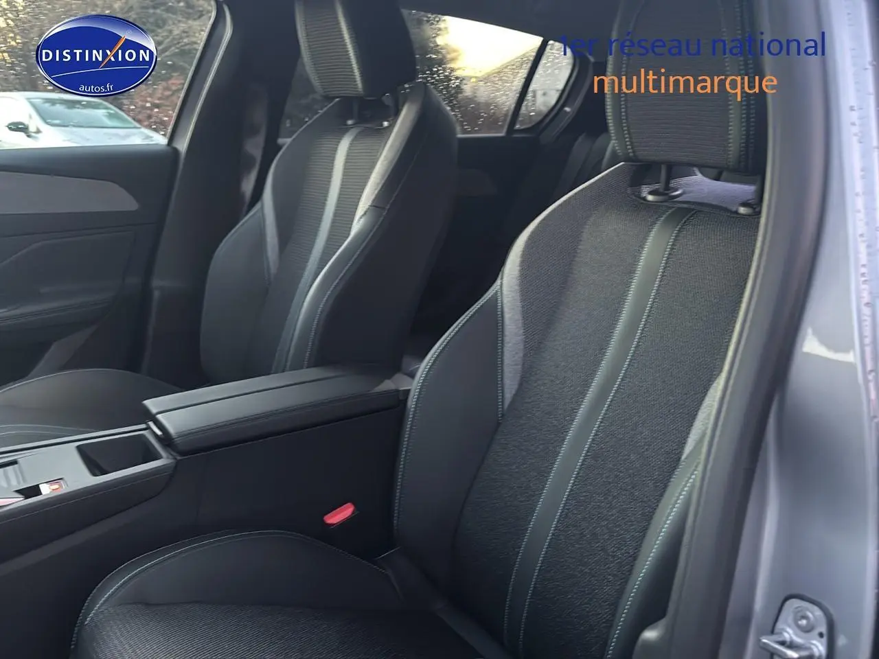 Vue intérieure côté droit sur les sièges avant gris foncé avec accoudoir central de la Peugeot 308 1.2 hybrid 145 allure 2025.