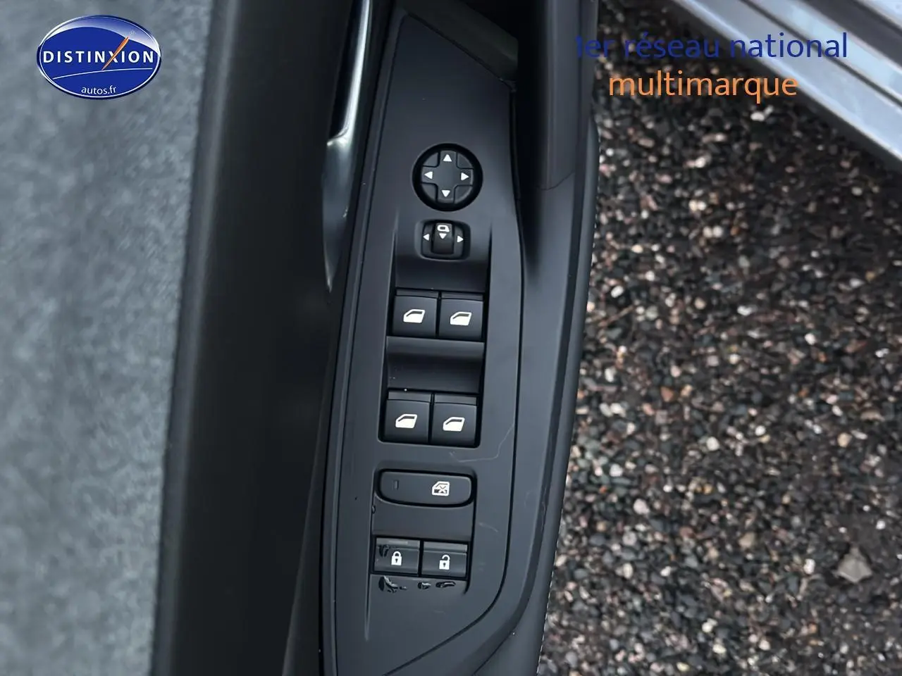 Commande des vitres électriques et des rétroviseurs côté conducteur de la Peugeot 308 gris Artense, porte ouverte sur sol gravillonné.