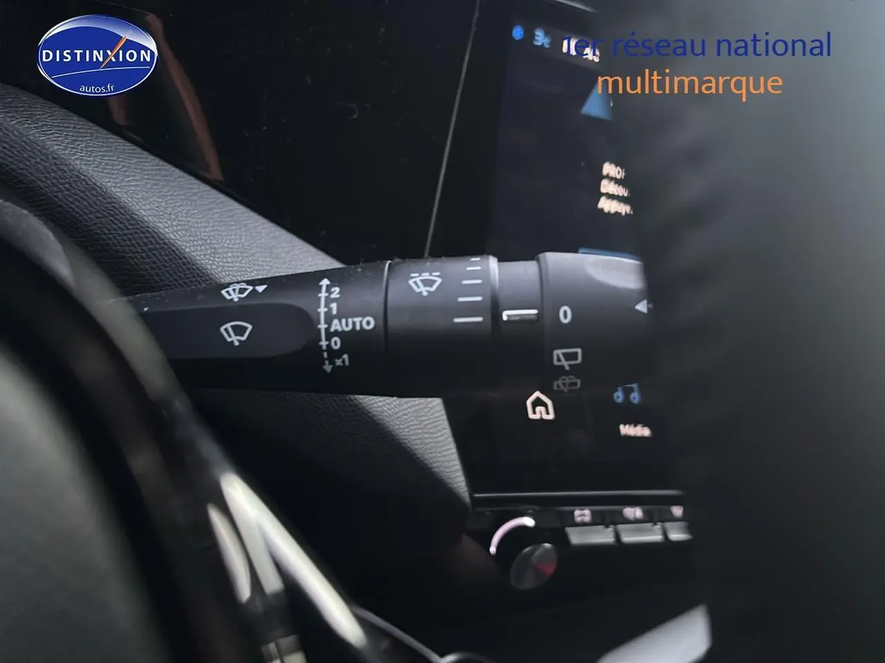 Gros plan sur la commande des essuie-glaces à gauche du volant dans l'habitacle gris d'une Peugeot 308 2025.