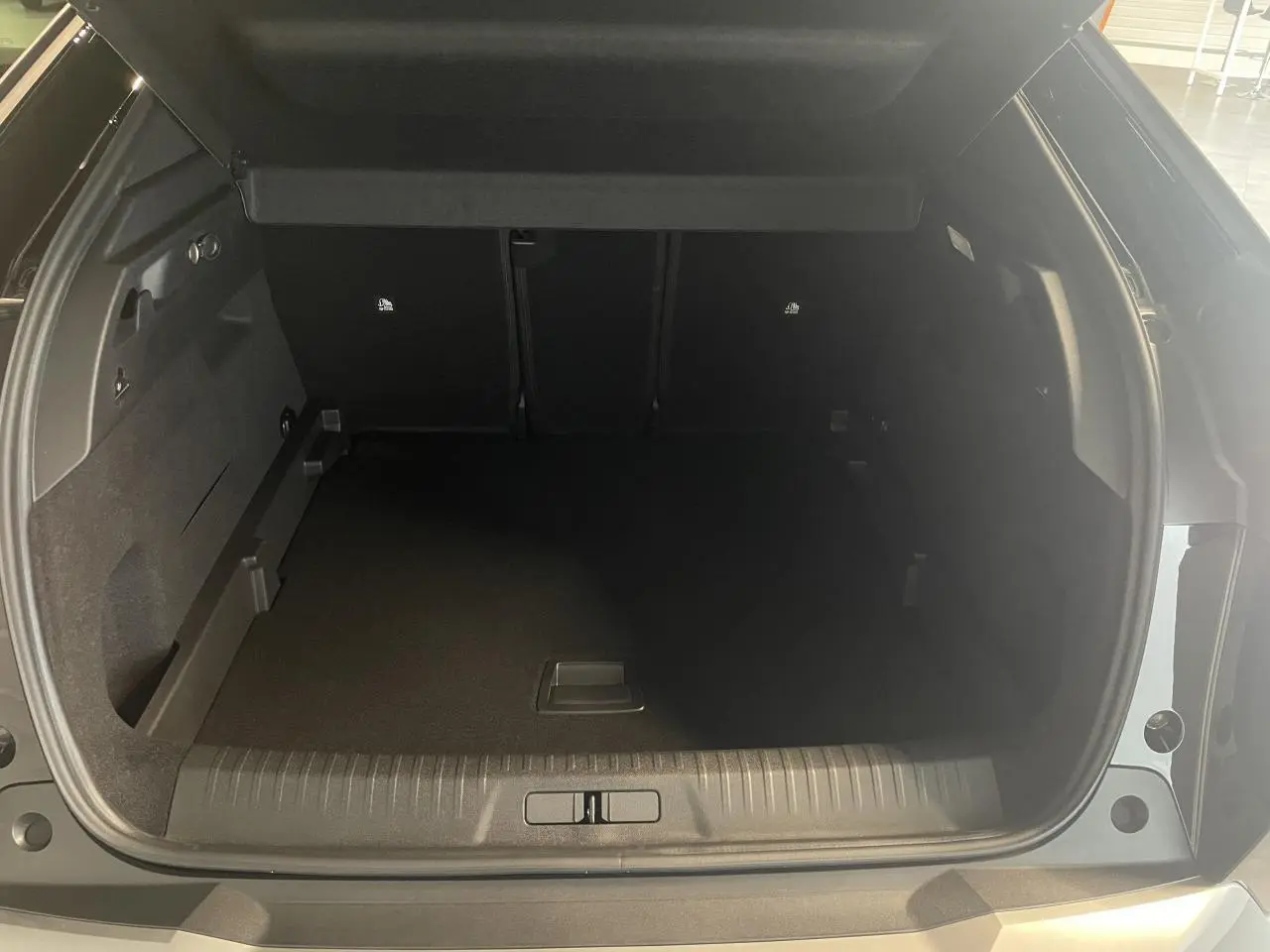 Coffre ouvert vu de l'arrière d'un Peugeot 3008 noir métallisé, montrant l'espace de chargement vide.