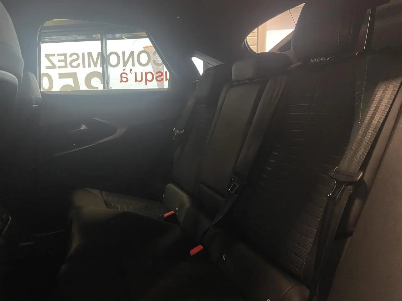 Vue intérieure côté droit des sièges arrière noirs du Peugeot 3008 1.2i Hybrid GT 2025 avec ceintures de sécurité visibles.