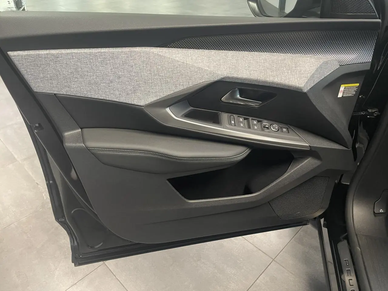 Vue intérieure de la porte avant gauche du Peugeot 3008 noir métallisé, avec garniture tissu et commandes électriques.