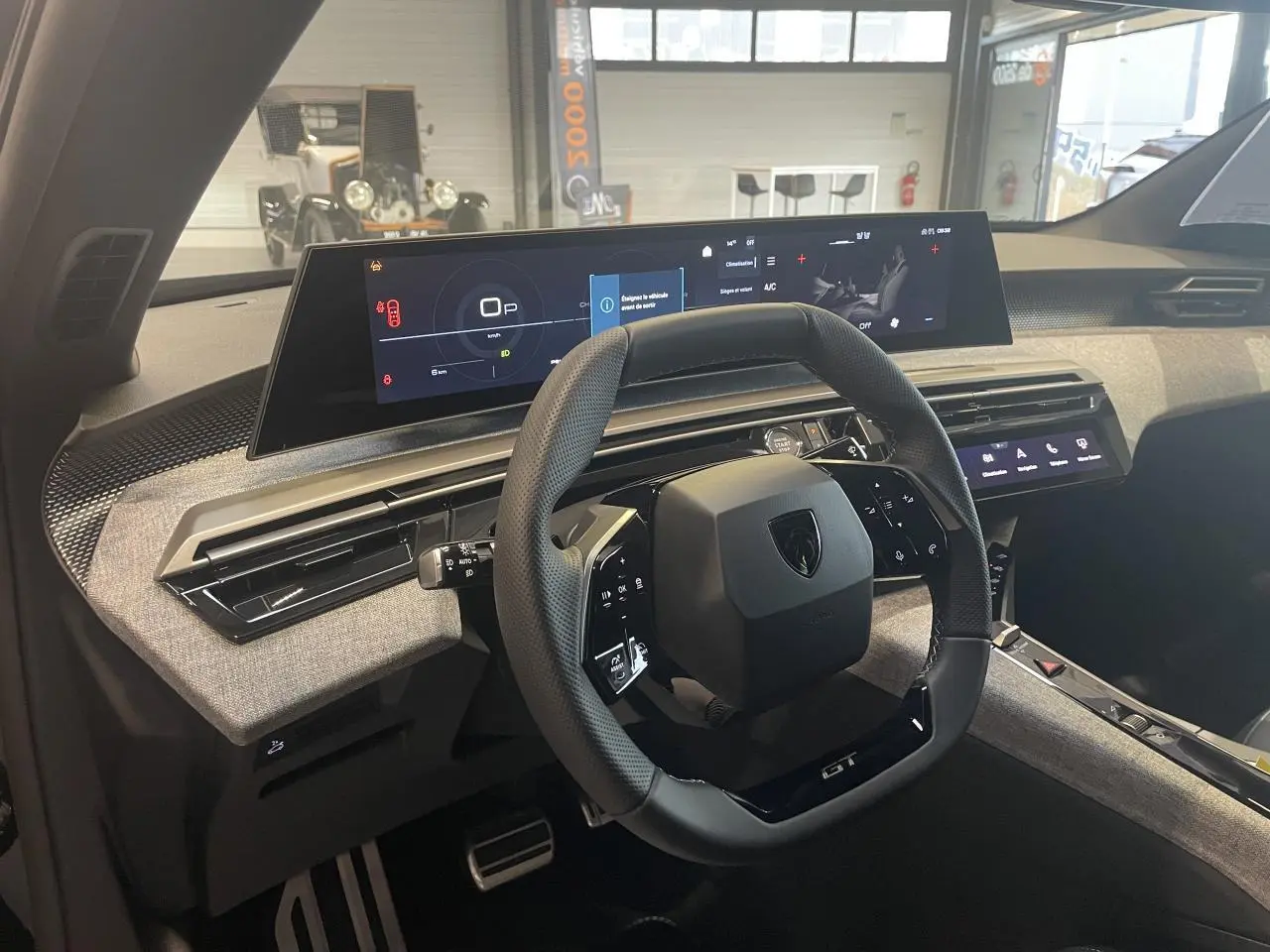 Vue intérieure du poste de conduite du Peugeot 3008 GT 2025, volant compact noir et tableau de bord numérique panoramique.