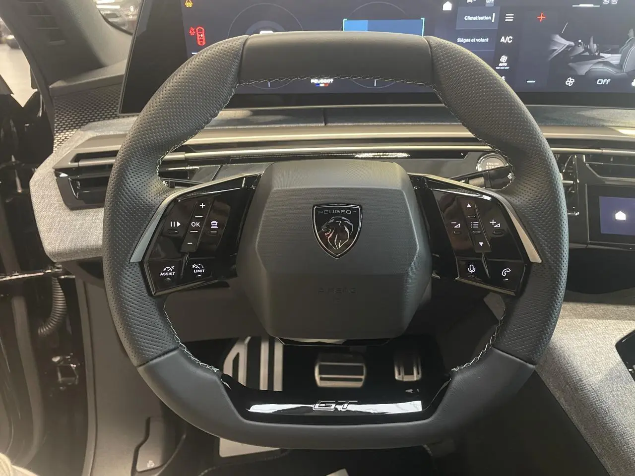 Vue rapprochée du volant compact noir perforé avec logo Peugeot et badge GT du Peugeot 3008 hybride 2025.