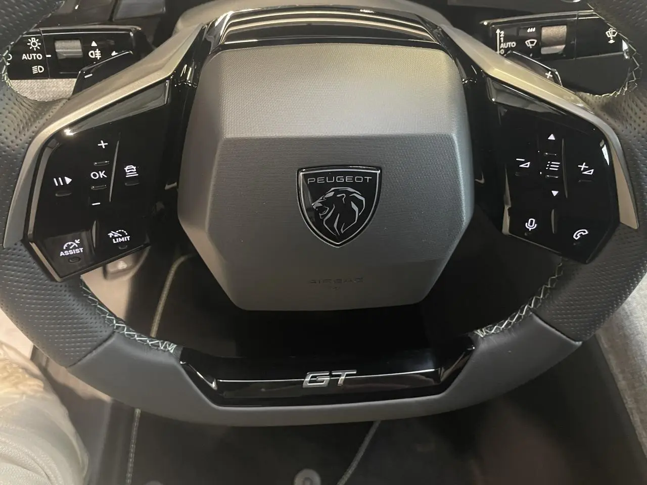 Vue rapprochée du volant noir perforé Peugeot 3008 GT avec commandes intégrées et logo central.