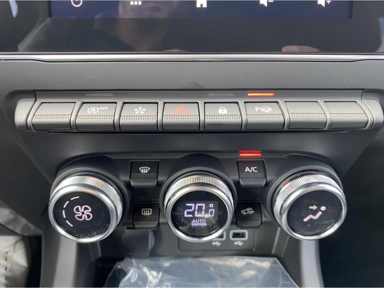 Gros plan sur la console centrale du Renault Arkana 2022, boutons de climatisation et commandes en ligne horizontale.