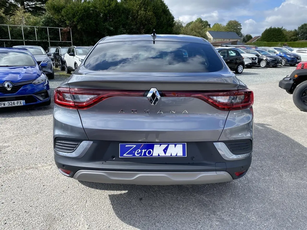 Vue arrière d'un Renault Arkana gris foncé 2022 avec feux LED et antenne aileron de requin sur un parking.