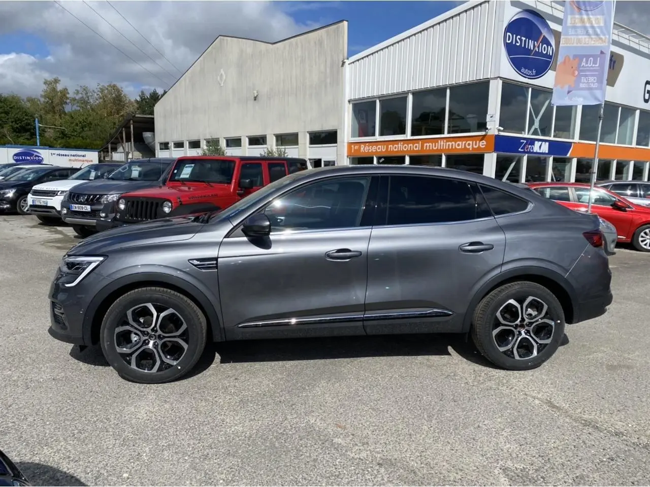 Profil droit d'un Renault Arkana gris foncé 2022 avec vitres surteintées et jantes alliage distinctives, stationné en extérieur.