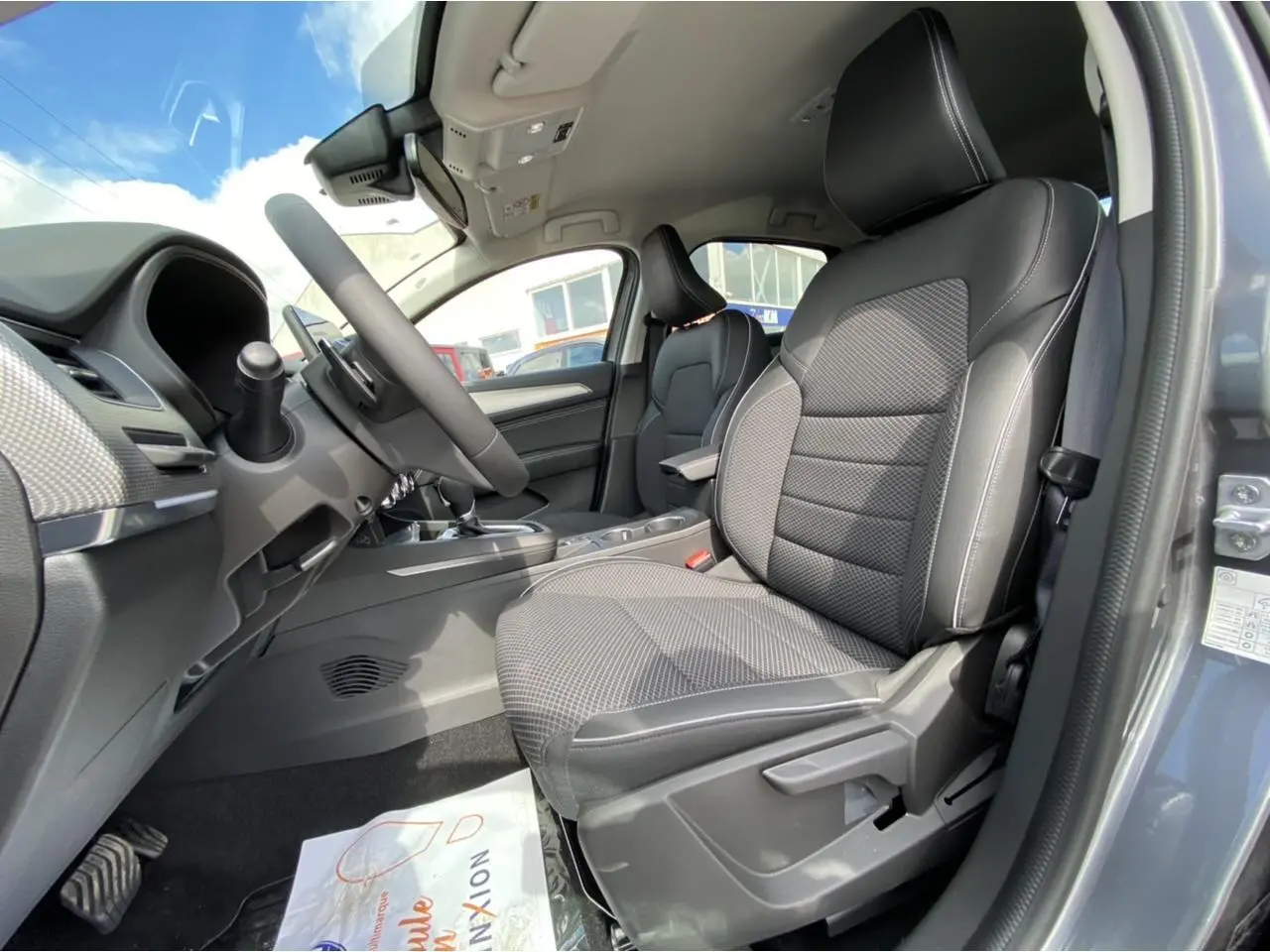 Vue intérieure côté conducteur du Renault Arkana gris foncé 2022, mettant en valeur les sièges et le volant.