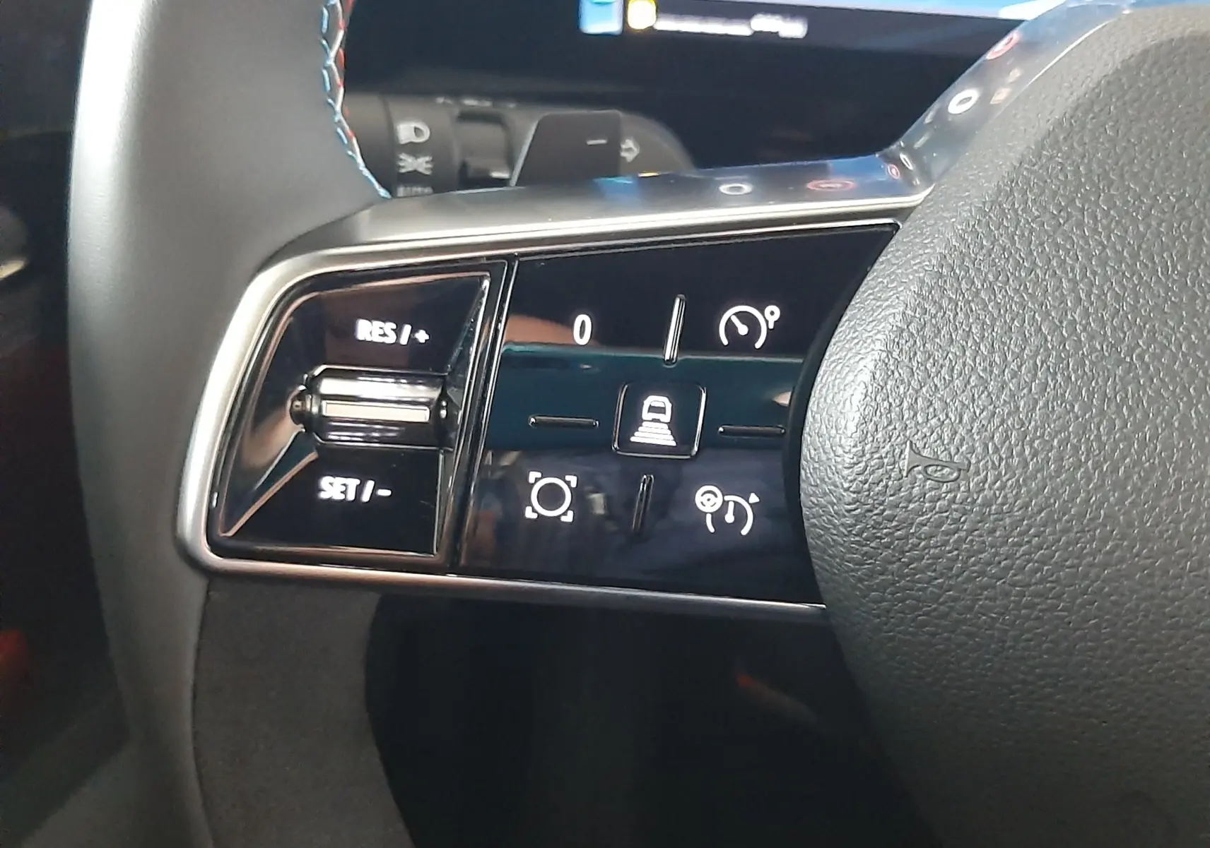 Gros plan sur les commandes de régulateur de vitesse au volant du Renault Austral E-Tech gris schiste satin.