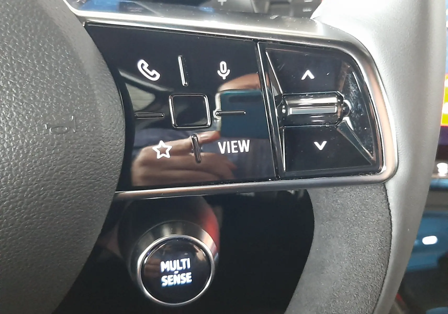 Gros plan sur les commandes au volant noir brillant du Renault Austral E-Tech hybride 2025, avec bouton Multi Sense éclairé.