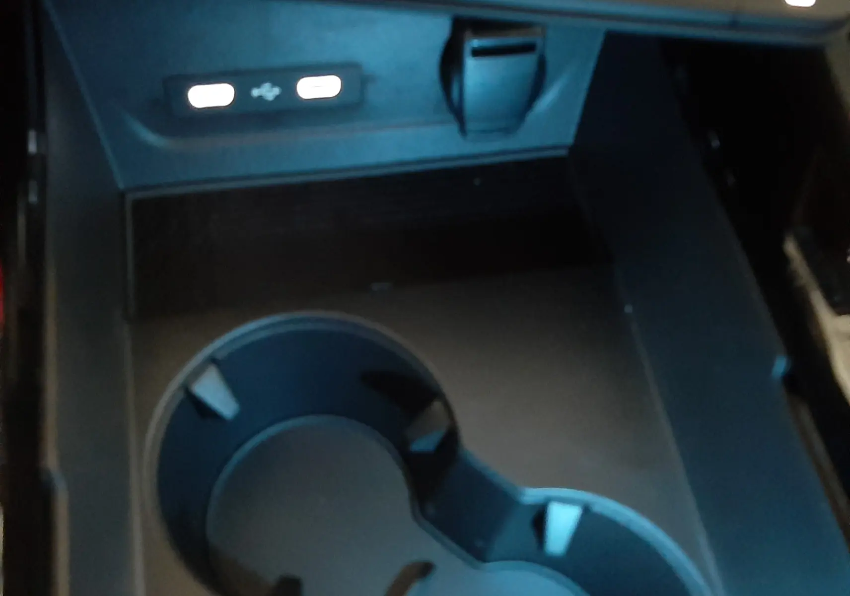 Gros plan sur la console centrale du Renault Austral E-Tech 2025, montrant porte-gobelets et ports USB éclairés.