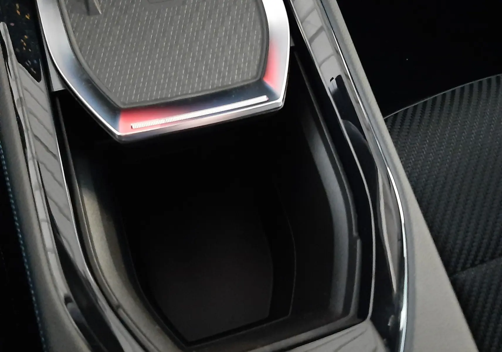 Vue rapprochée de la console centrale noire brillante avec rangement ouvert du Renault Austral E-Tech hybride 2025.