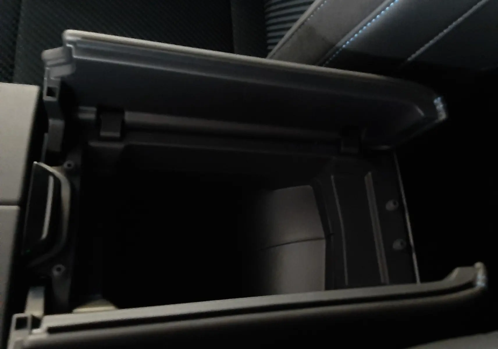 Vue rapprochée de la console centrale ouverte avec rangement intérieur sur Renault Austral gris schiste satin.