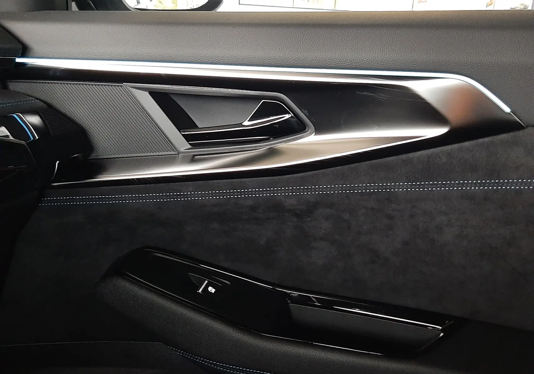 Détail de la porte côté gauche du Renault Austral E-Tech gris schiste satin, avec insertions noires et surpiqûres bleues.