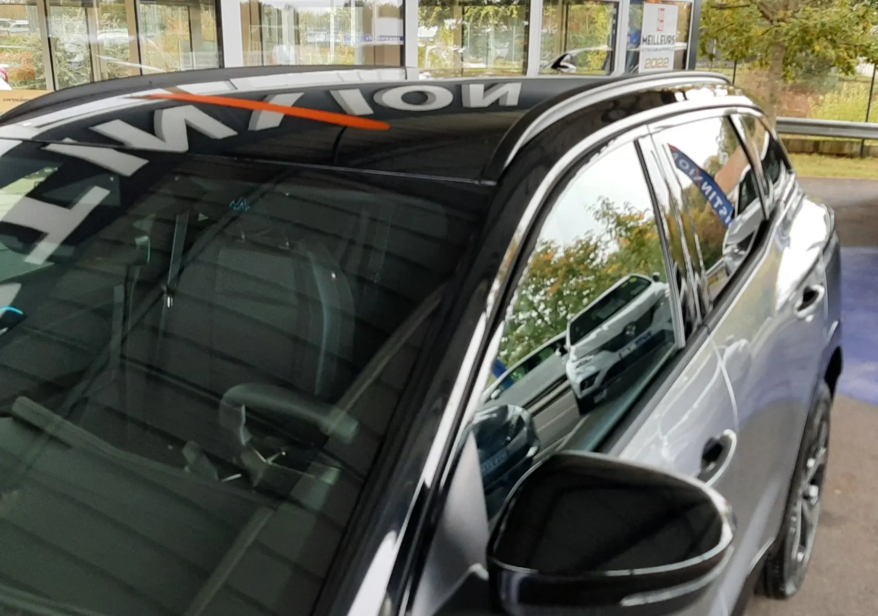 Vue 3/4 avant droit du Renault Austral gris schiste satin avec toit noir brillant et rétroviseur assorti.