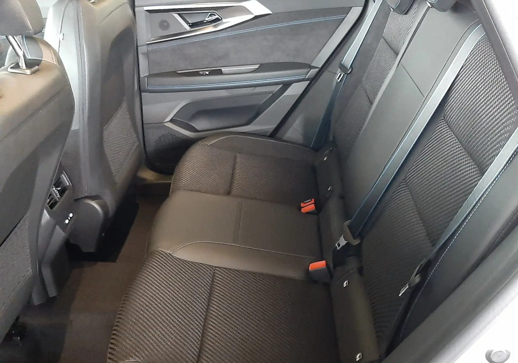 Vue intérieure côté droit des sièges arrière noirs en tissu et cuir du Renault Austral 2025, avec ceinture et porte ouvert.