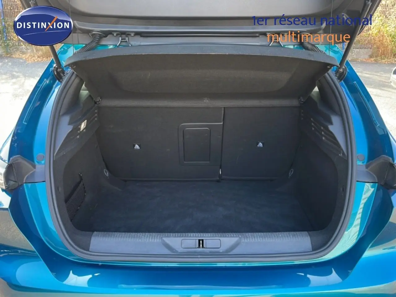 Coffre ouvert vu de l'arrière d'une Peugeot 308 2024 bleu obsession métal, montrant un espace de rangement vide.