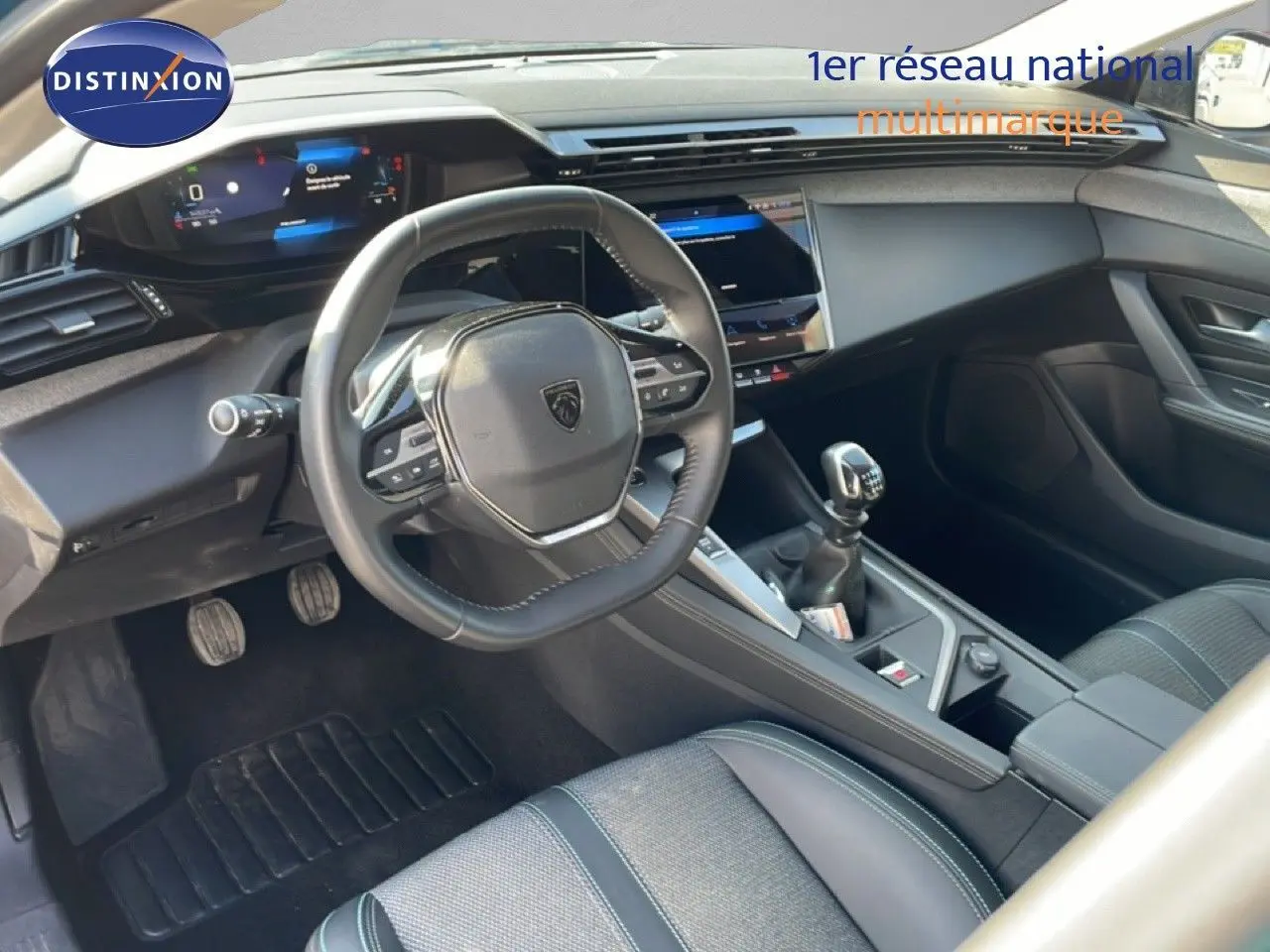 Vue intérieure côté conducteur de la Peugeot 308 2024, volant cuir multifonction et levier de vitesse manuelle visibles.