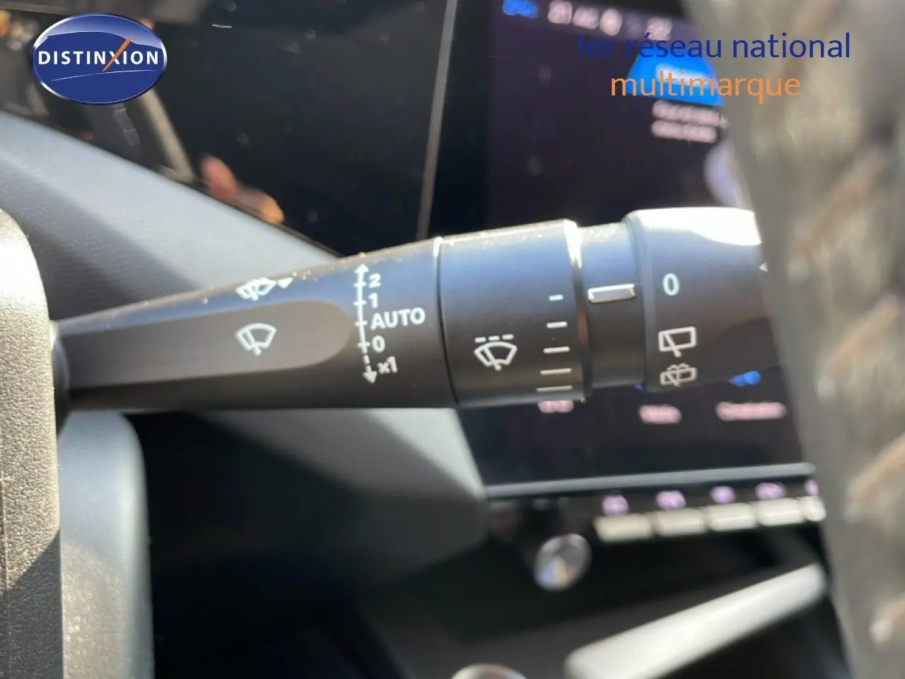 Gros plan sur la commande d’essuie-glace à gauche du volant dans l’habitacle d’une Peugeot 308 bleu obsession métal 2024.