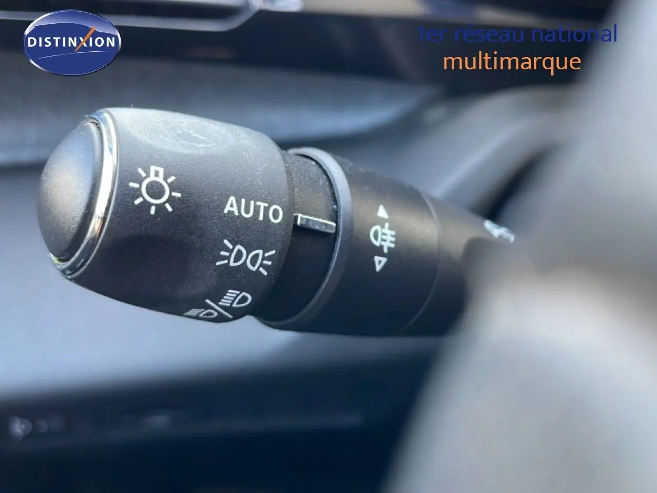 Gros plan sur la commande des feux automatiques dans l’habitacle d’une Peugeot 308 Bleu Obsession 2024.
