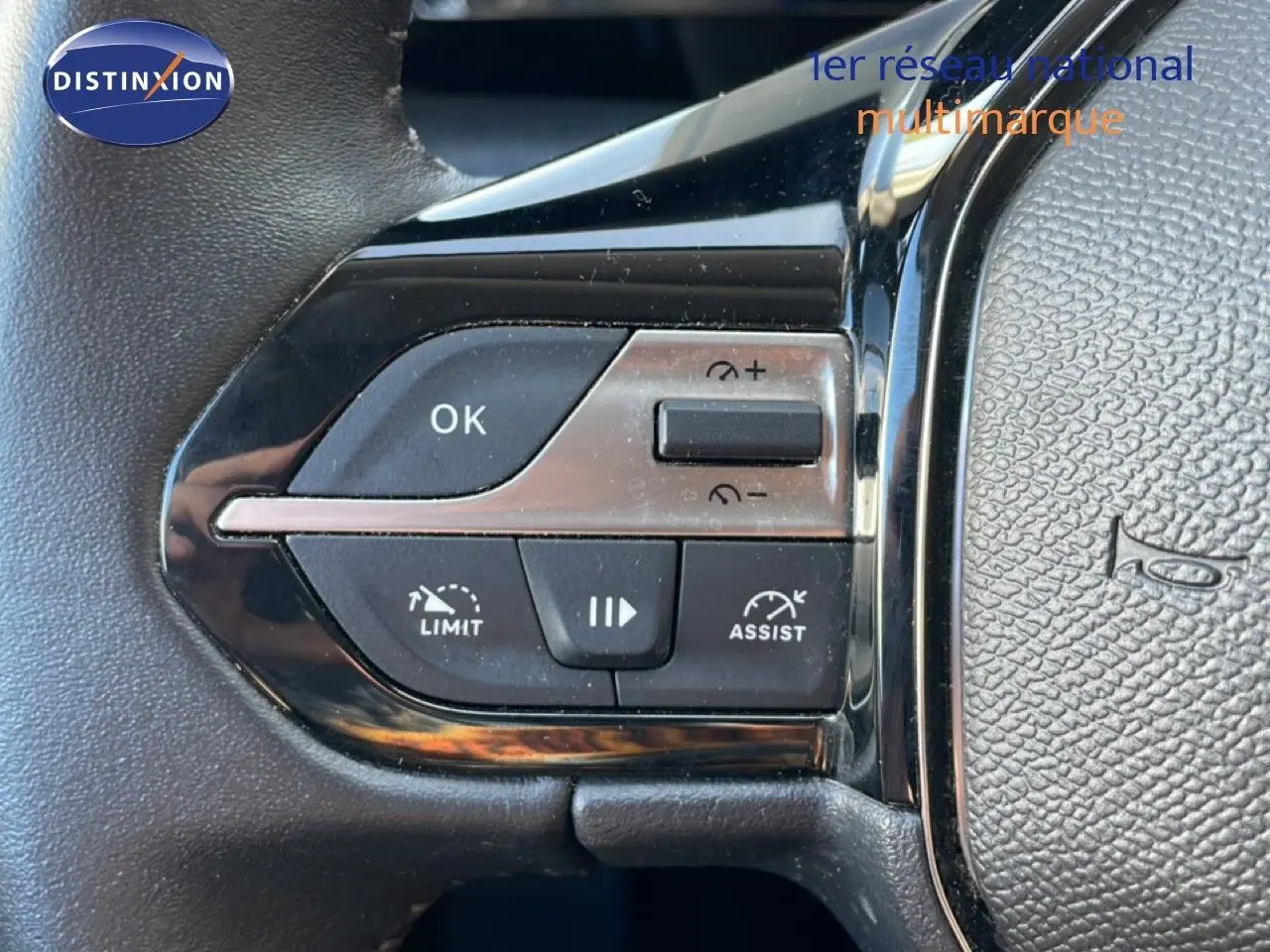 Gros plan sur les commandes au volant de la Peugeot 308 2024, boutons noirs et chrome avec fonctions limiteur et assist.
