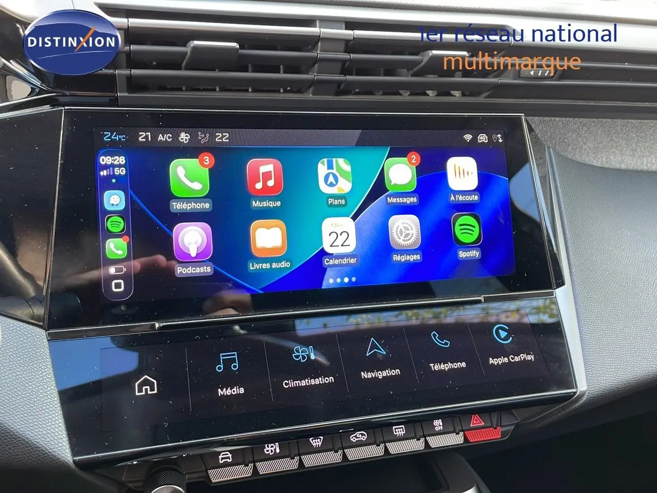 Écran tactile central de la Peugeot 308 2024 en bleu obsession, affichant Apple CarPlay et commandes climatisation.