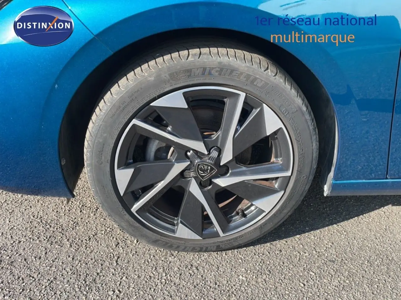 Gros plan sur la roue avant gauche de la Peugeot 308 bleu obsession métal avec jante alliage bicolore 2024.
