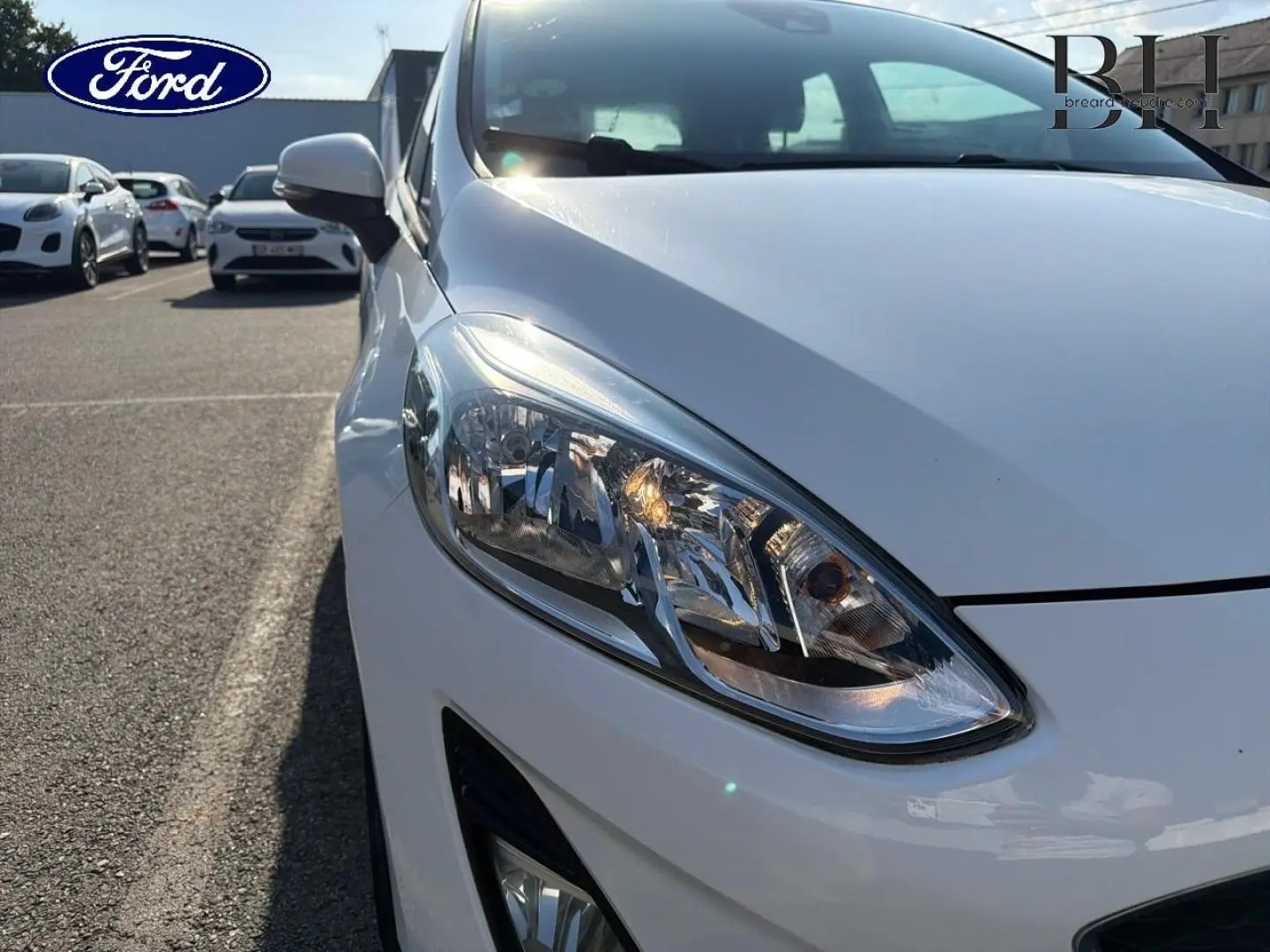 Gros plan sur l'avant droit blanc glacier d'une Ford Fiesta 2018, mettant en valeur le phare et le rétroviseur.