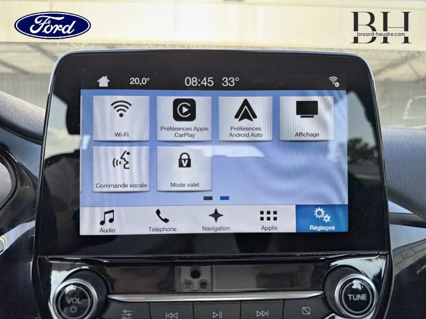 Écran tactile central de la Ford Fiesta 2018 affichant les réglages connectés, avec commandes vocales et navigation visibles.