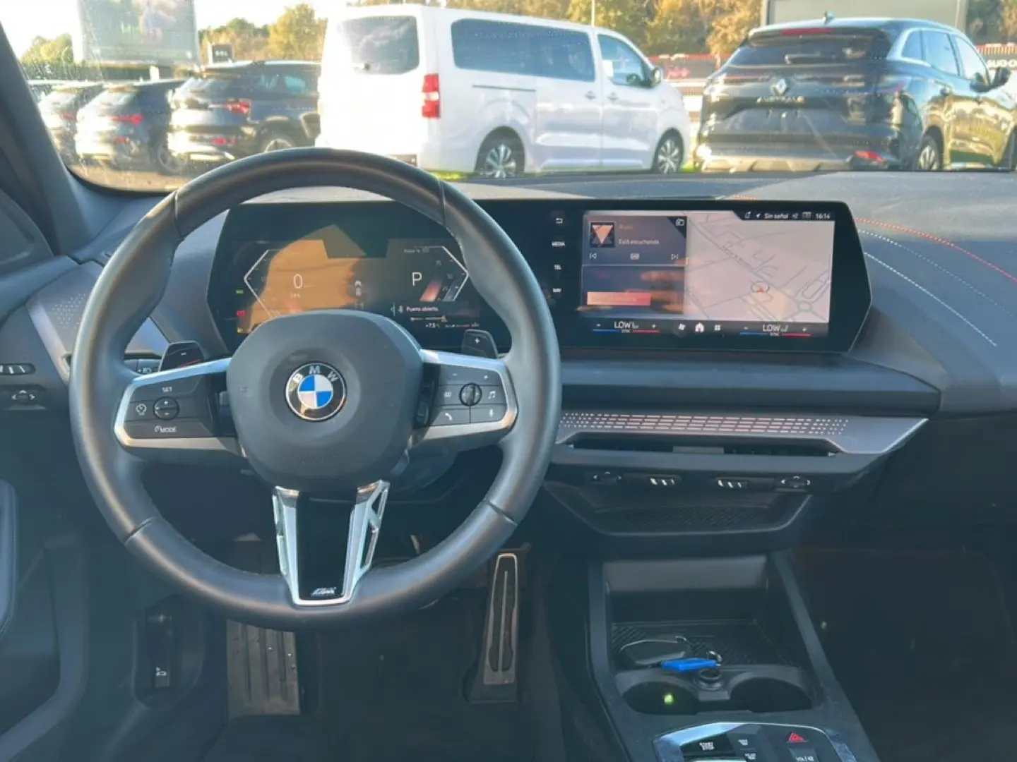 Vue intérieure centrée sur le volant BMW Série 1 2025 avec tableau de bord numérique et écran tactile.