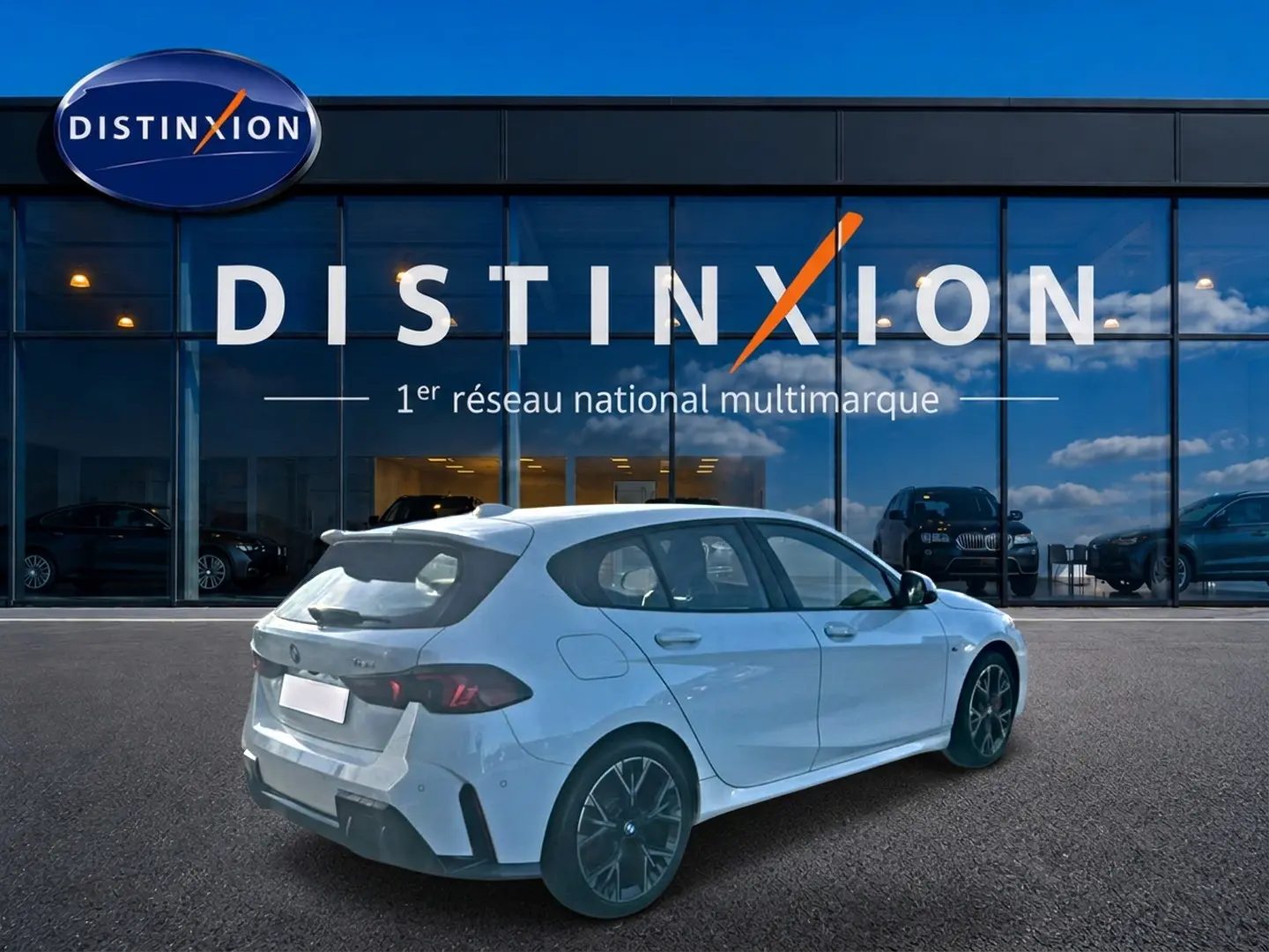 BMW Série 1 blanc alpin vue 3/4 arrière droit, jantes 18 pouces bicolores, devant showroom Distinxion.