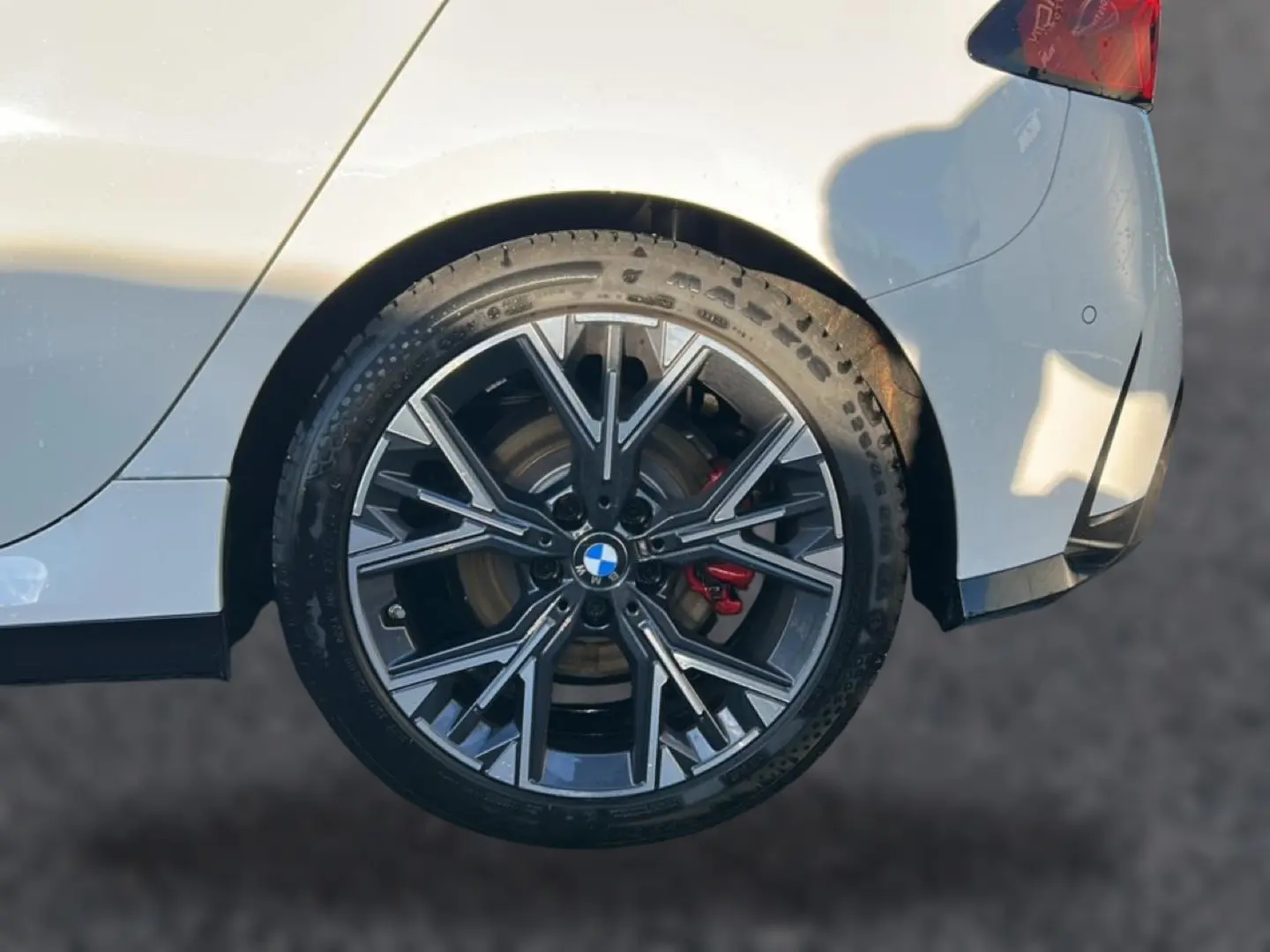 Gros plan sur la jante 18 pouces bicolore en Y d’une BMW Série 1 blanche alpine, avec étrier de frein rouge visible à l’arrière.