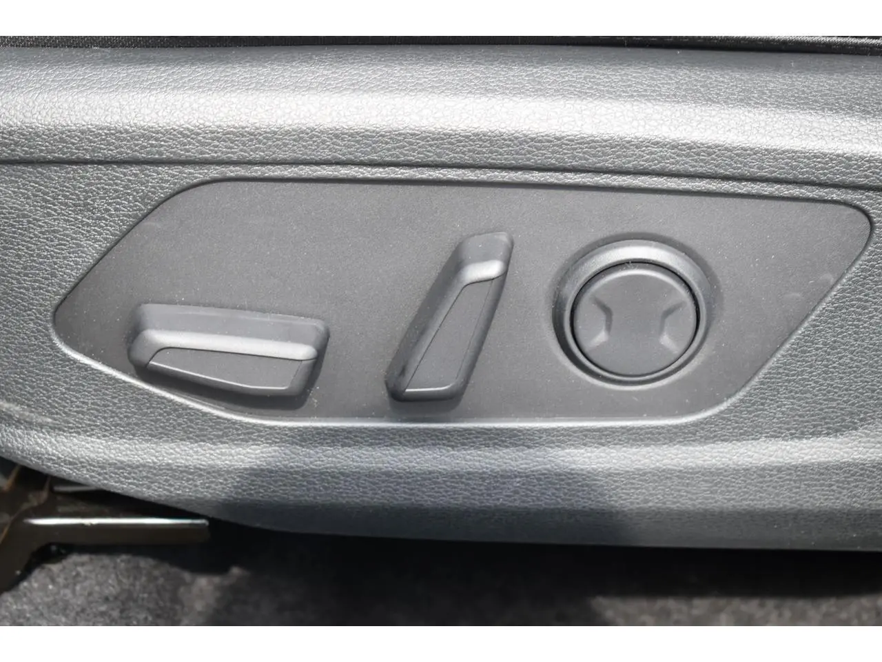 Gros plan sur les commandes électriques de réglage du siège avant du KIA SPORTAGE noir hybride 2026.