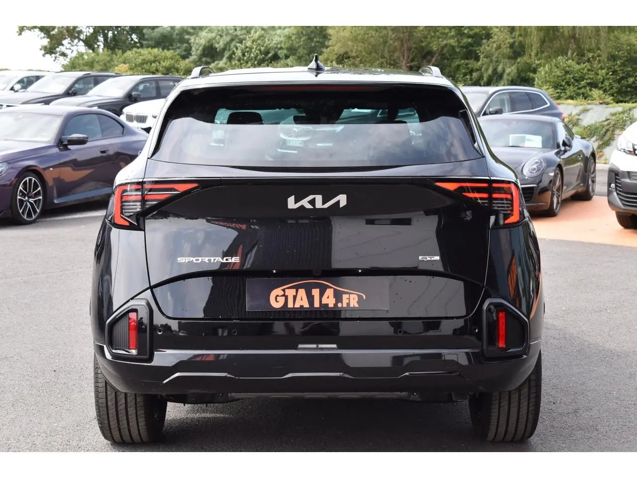 Vue arrière d'un KIA Sportage hybride noir 2026 avec feux LED distinctifs et logo moderne sur le hayon.
