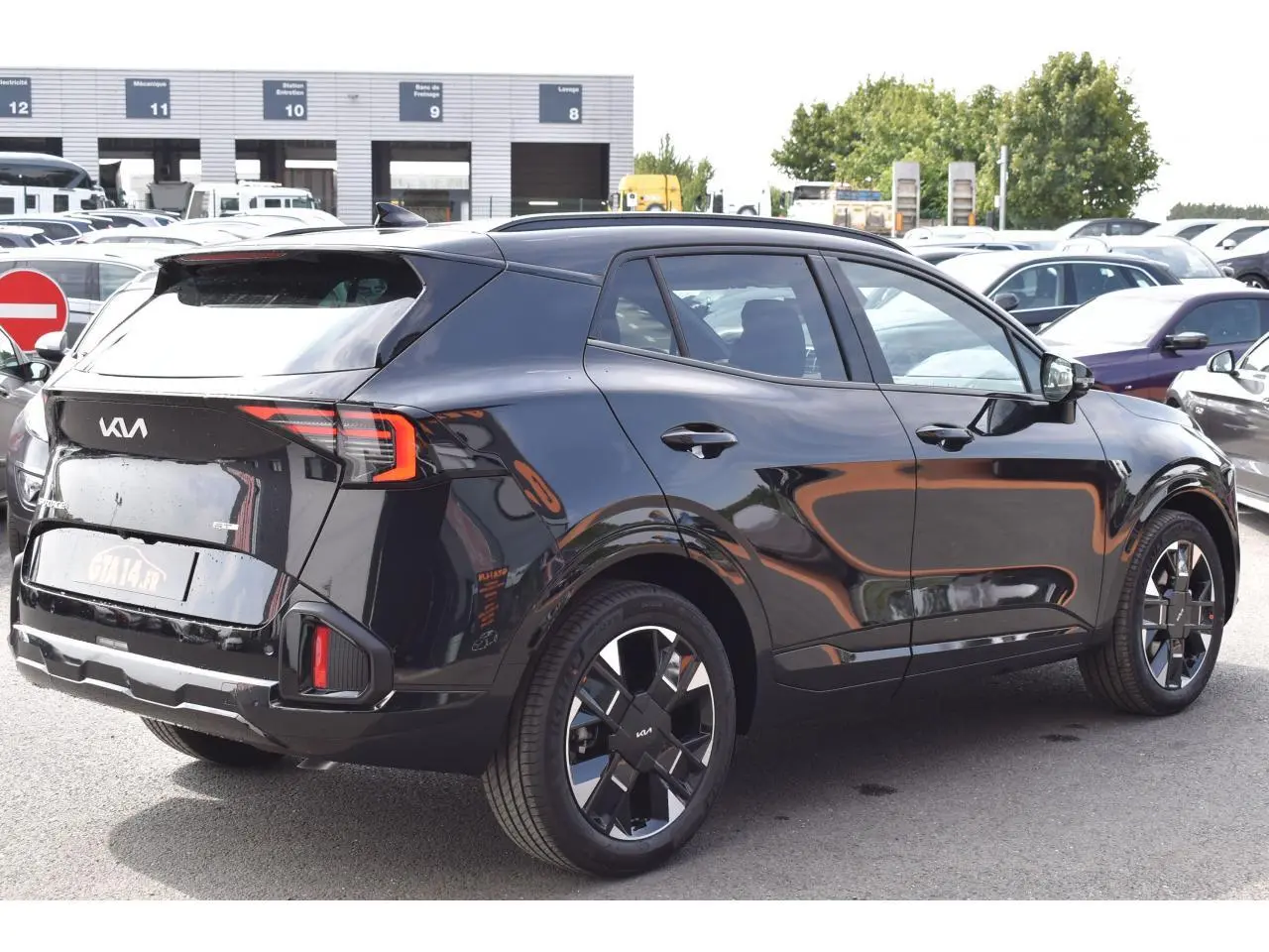 Vue 3/4 arrière droite du Kia Sportage hybride noir 2026 avec jantes 19 pouces et feux LED distinctifs.
