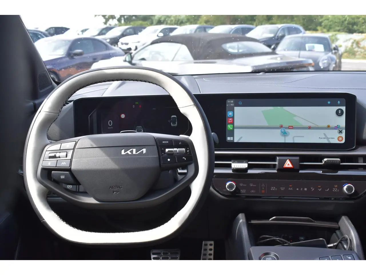 Vue intérieure centrée sur le volant noir et blanc du Kia Sportage 2026 avec écran tactile et navigation affichée.