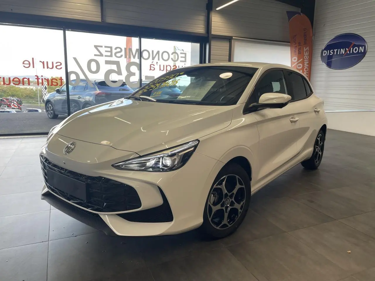 Vue 3/4 avant droite d'une MG3 blanche 2026 avec jantes alliage et phares LED en showroom.