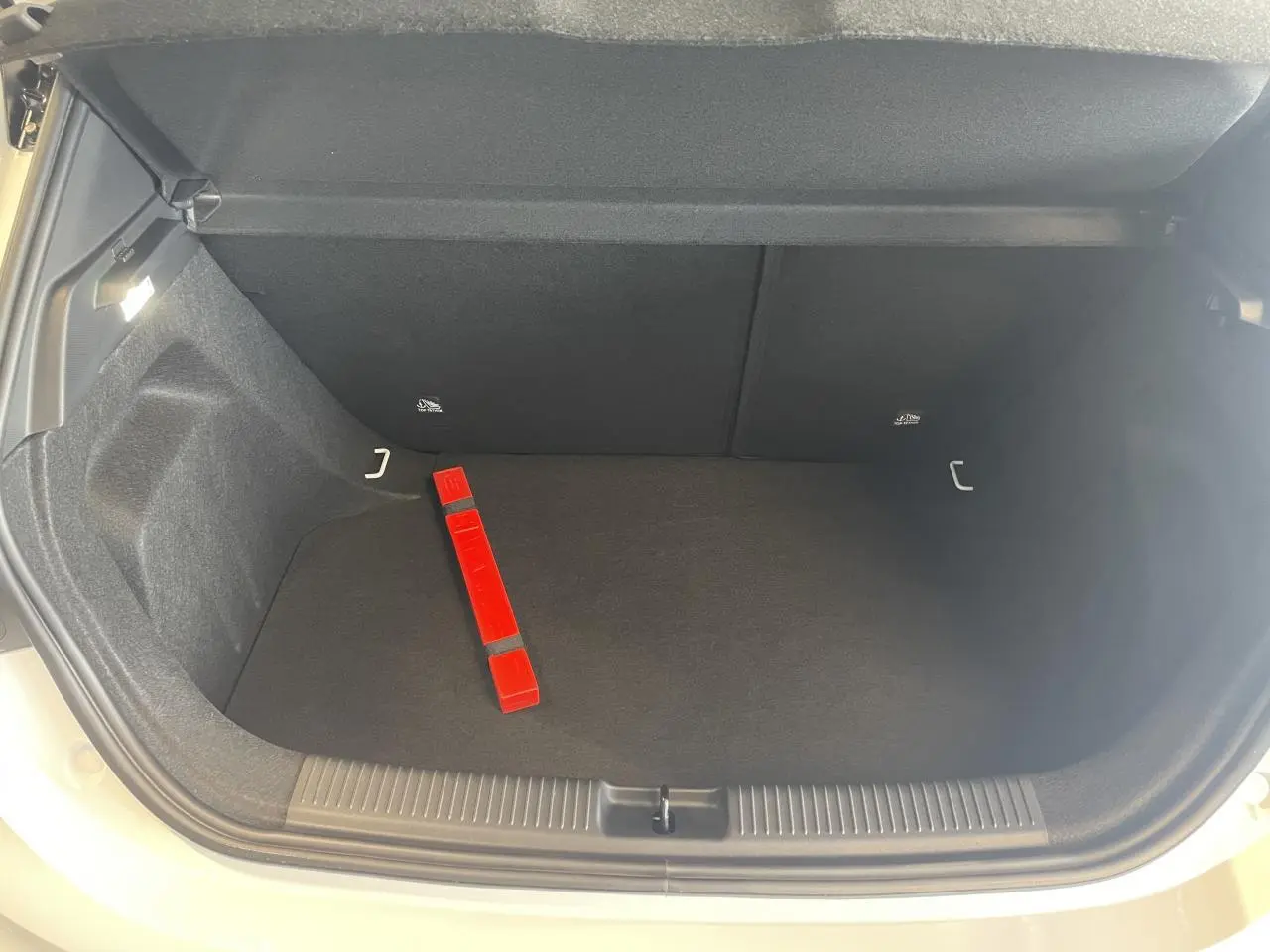 Coffre ouvert vu de face d'une MG3 blanche, avec intérieur noir et triangle de signalisation rouge posé au sol.