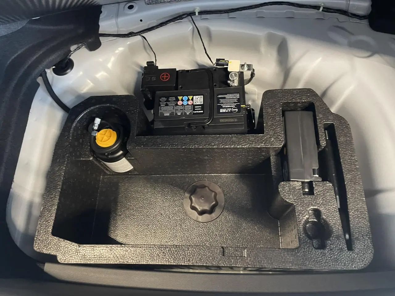 Vue plongeante sur le coffre blanc du MG3 1.5 Hybrid+ 2026, montrant la batterie et le rangement en mousse noire.