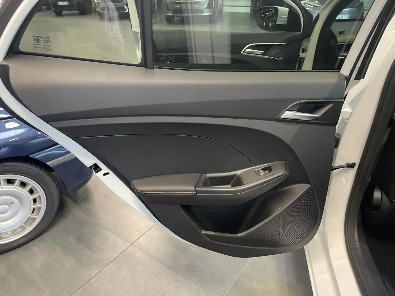 Vue intérieure de la porte arrière gauche blanche du MG3 1.5 Hybrid+ Luxury avec accoudoir et commande de vitre.