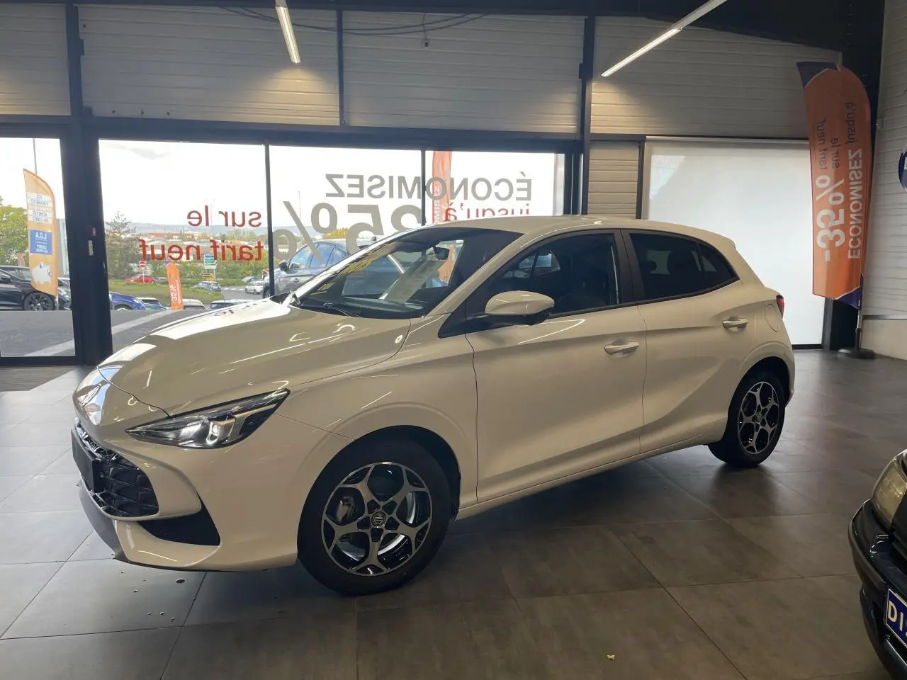 Vue 3/4 avant droite d'une MG3 blanche 2026 avec jantes alliage et vitres surteintées en showroom.