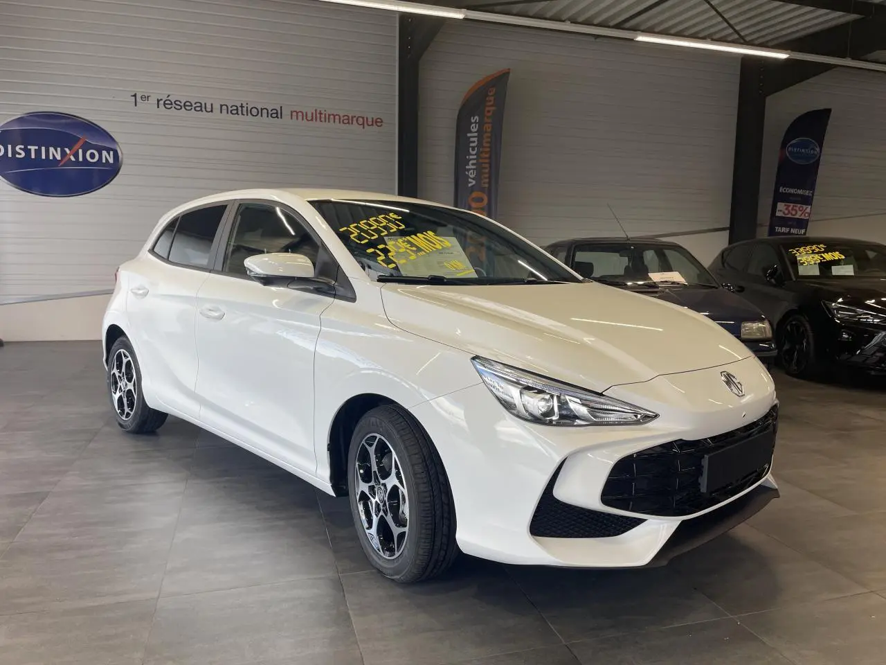 Vue 3/4 avant d'une MG3 1.5 Hybrid+ blanche avec jantes alliage 16'' dans un showroom intérieur.