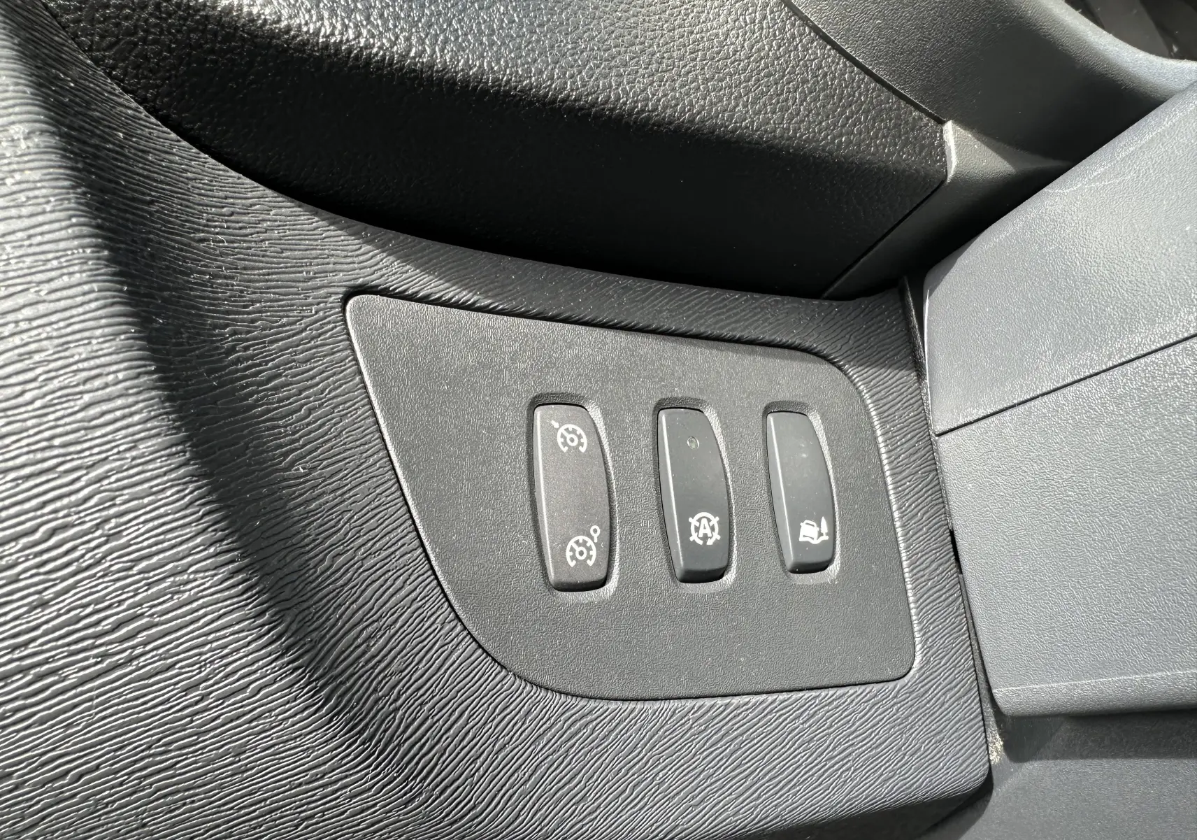 Gros plan sur les trois boutons de commande du tableau de bord intérieur noir du Nissan NV250 blanc, version 2020.