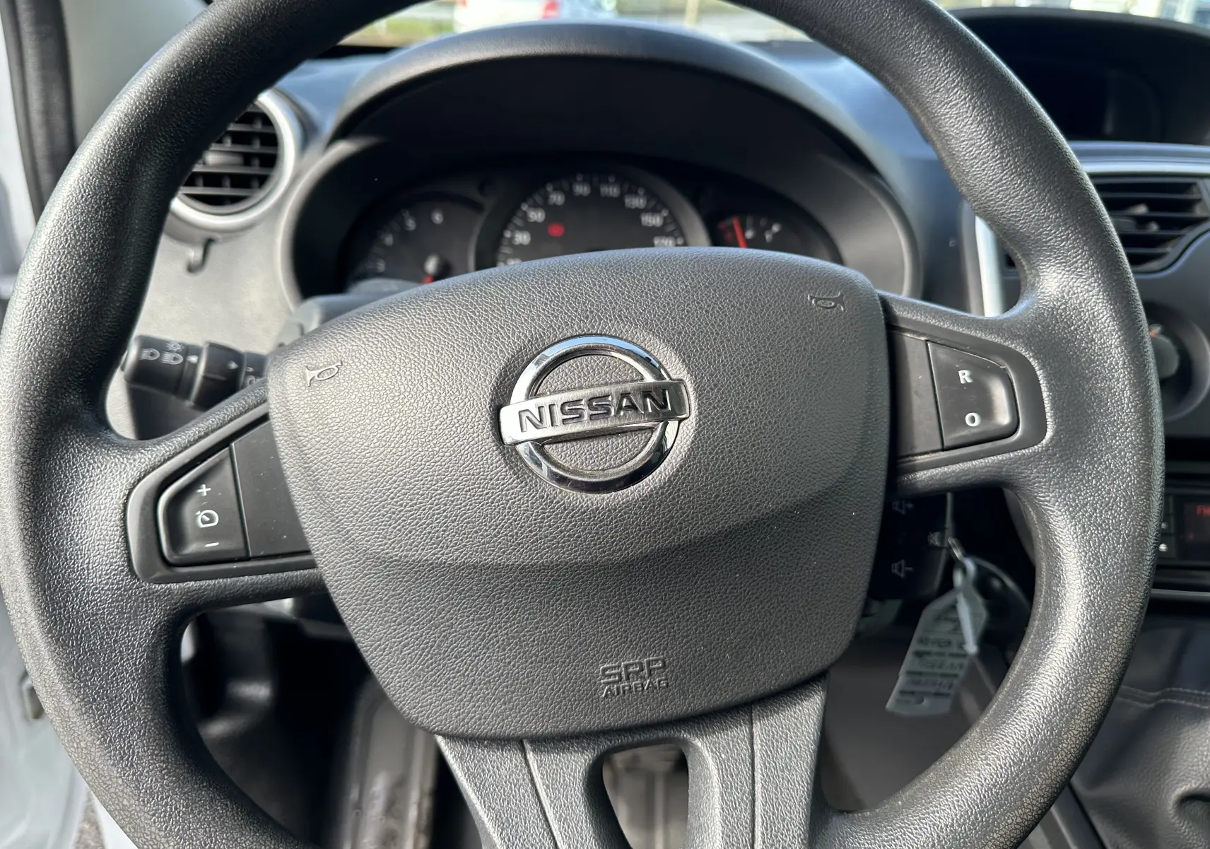 Vue rapprochée du volant noir avec logo Nissan au centre du tableau de bord du NV250 blanc de 2020.