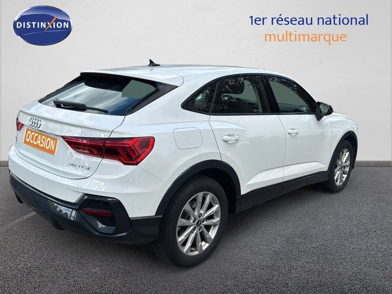 Audi Q3 Sportback blanc vue 3/4 arrière côté droit, avec feux arrière LED et jantes alliage 18 pouces.